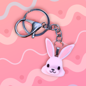 A pink emily and woo keychain on a pink background